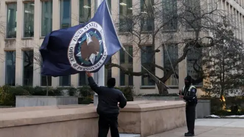 The flag of the Office of Personnel Management is lowered outside its Washington headquarters.