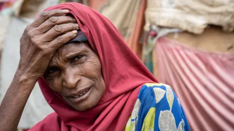 Getty Images Woman with a red headscarf with head in hands