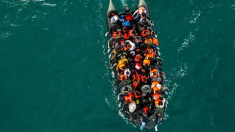 Reuters A drone shot showing an inflatable dinghy carrying migrants navigating towards the UK in the English Channel in August.