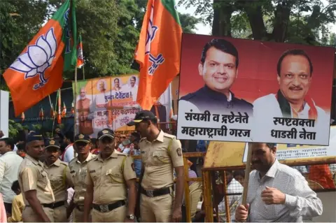 AFP Bharatiya Janata Party (BJP) supporter carries a poster of Chief Minister of the western Indian state of Maharashtra Devendra Fadnavis and Nationalist Congress Party (NCP) leader and deputy Chief Minister Ajit Pawar at a victory rally outside the headquarters in Mumbai on November 23, 2019.