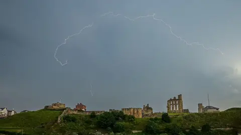 A Figment of your Imagination Rolling grey clouds and small bursts of lightning light up the ruins of Tynemouth Priory on a hill above the town