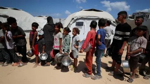 Reuters Displaced children queue for food at a charity kitchen in Gaza City