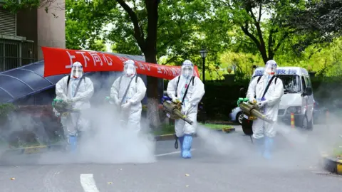 Getty Images Image shows health workers disinfecting streets