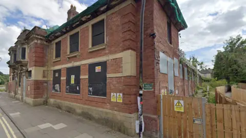 The outside of a redbrick building which once housed Durham City Baths. The building is now derelict and boarded up.