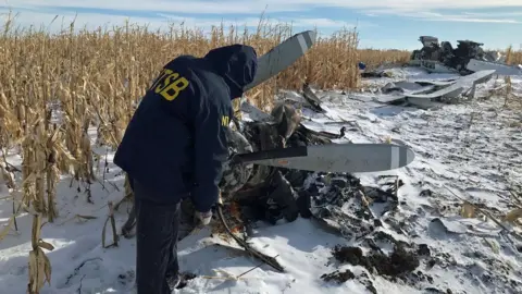 National Transportation Safety Board An investigator looks at wreckage of plane in the snow