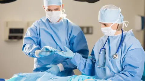 Surgical nurse assisting surgeon during operation in hospital