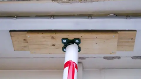 A close up of a prop attached to wooden plank, attached to a ceiling in a hospital.