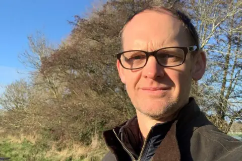 Welsh government Dr Richard Irvine, chief veterinary officer for Wales standing in a field wearing a brown coat.