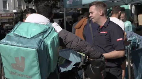 A deliveroo rider speaking to a firefighter in Bristol city centre