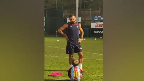 Alan Kearney Image shows Isaac sitting on a training football pitch. Salah stands in front of him with his hands on his hips. 
