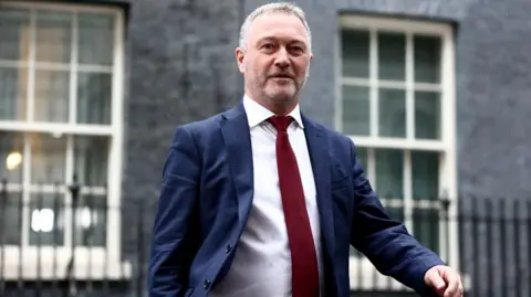 Steve Reed wearing red tie and walking