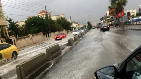 EPA Vehicles drive through rain water after a sudden thunderstorm, at a street of Amman, Jordan, 25 October 2018