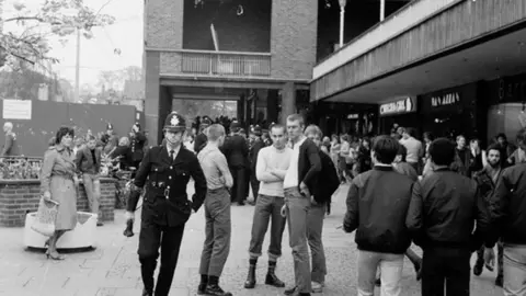 Alan Van Wijgerden A police officer passes skin heads in Coventry