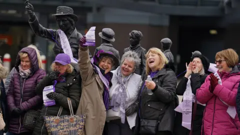 PA Media Seven women stand in front of a statue  qhidddiqxxiqxdinv