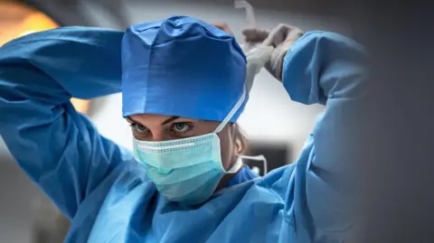 A surgeon is wearing a blue mask to prevent infection before surgery.