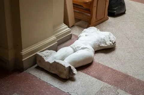 A statue, too heavy to move underground, lies on the floor of the museum's atrium