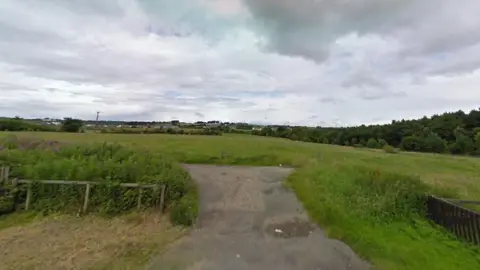 A green space in Leadgate, County Durham, where there is a proposal to build 97 new homes. It is an area of fairly wild grassland bordered by trees and hedges. A wide, concrete path leads a short way into the main field.