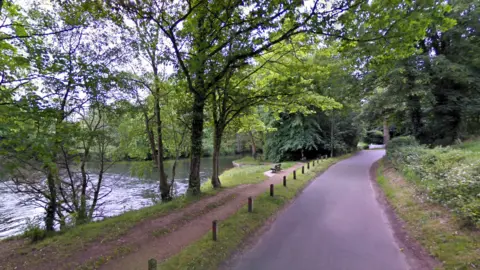 Google A wooded area around Horstead Mill, showing a narrow road and a footpath running along the edge of a waterway