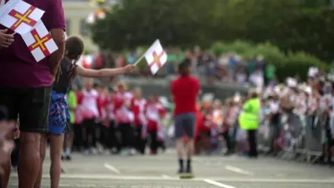 BBC Crowds lining the street for the Island Games 2023 opening ceremony