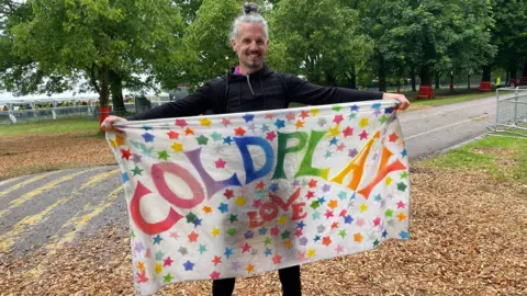 Danny Fullbrook/BBC Timo Kankasta holding a hand made Coldplay sign