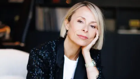 Em Marcovecchio Songwriter Miranda Cooper, wearing a black sparkly jacket and resting her head on her arm