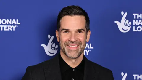 Getty Images Gethin Jones, he is wearing a black shirt. He has dark brown hair and beard. 