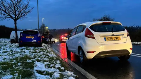 A blue Ford Focus is parked on the side of a snowy road.