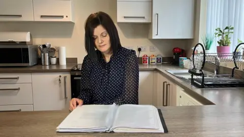 Phil Bodmer/BBC Katie at a table with some paperwork