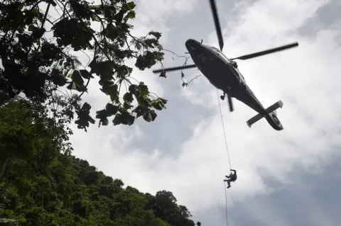 AFP A Thai Airforce worker drops in by helicopter into a clearing in the forest near a possible overground opening to the Tham Luang cave