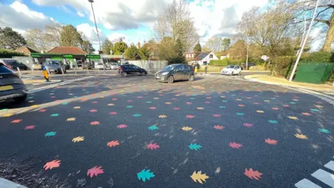 Cars driving across one of the rainbow leaf roundabouts.