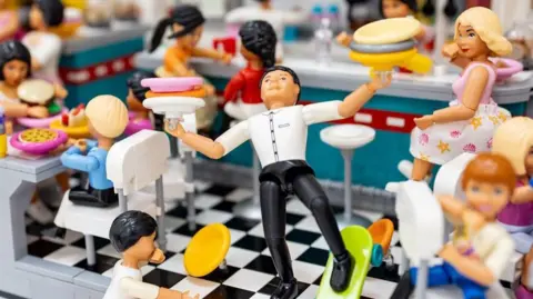 Bricktoria A busy 1950s diner scene made from Lego showing a waiter slipping on a skateboard