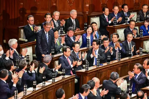 Getty Images Lawmakers applaud in parliament as Japan's Prime Minister Shigeru Ishiba stands after being reappointed as leader after the second round of a parliamentary vote to nominate a prime minister.