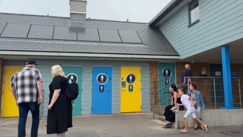 A group of people stood outside of the public toilets in Weymouth.
