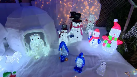 A light display showing snowmen on snow with an igloo