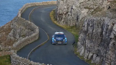 rally car driving along coast road