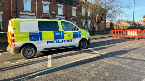 Police van and orange fencing