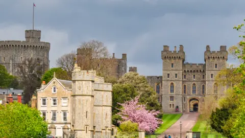 Windsor Castle with gate entrance leading into castle area.  Its tower is to the left with a flag flying.