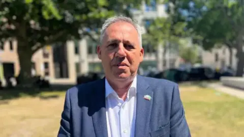 BBC Constable Jehan is wearing a blue blazer and a white shirt