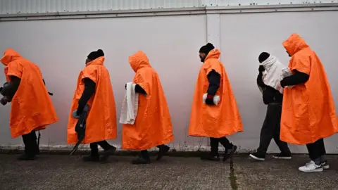 Getty Images Migrants standing in a queue waiting to be processed in Kent.