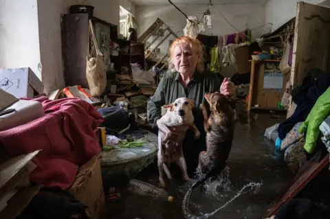 Evgen Maloletka An elderly woman carries her pets out from her flooded house