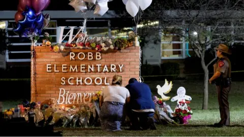 Reuters Stephanie and Michael Chavez of San Antonio pay their respects at a makeshift memorial outside Robb Elementary School,