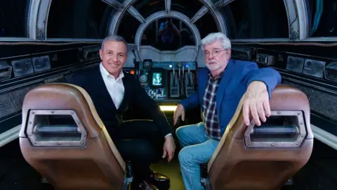 Getty Images Bob Iger (left) and Star Wars creator George Lucas inside Millennium Falcon: Smugglers Run at Star Wars: Galaxy's Edge at Disneyland Park in California