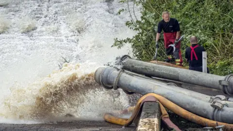 PA Media Water pumped out of the reservoir being put into River Goyt