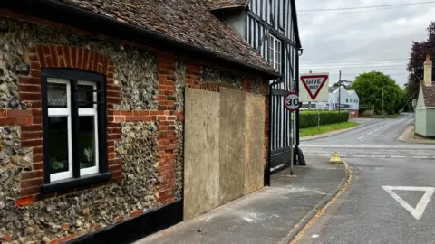 Matt Marvell/BBC The boarded up hole in the wall where the car had gone into the Bell Inn in Kennett, Newmarket