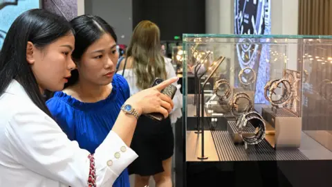 Getty Images Chinese shoppers look at watches in Haikou, China.