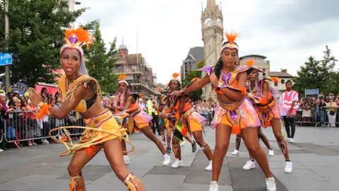 Leicester Caribbean Carnival Women dressed in colourful costumes dancing in the Leicester Caribbean Carnival troops in the parade near the clocktower in the city centre