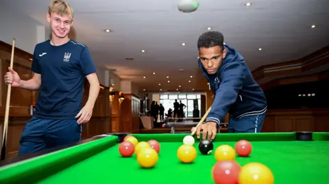 Getty Images Ukraine players playing pool in a hotel setting wearing dark blue team outfits 