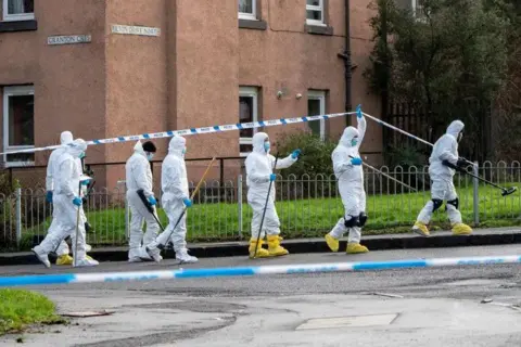 Pa Media Seven people in white forensic jass. There is a police tape.