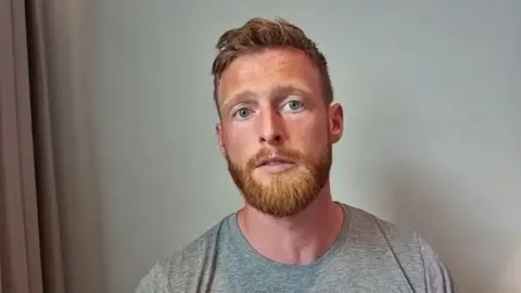 Liam Doherty, a man with ginger hair and a ginger beard who is wearing a grey T-shirt.