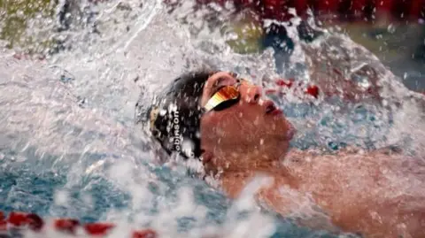 Harry Robinson swimming on his back in the pool.